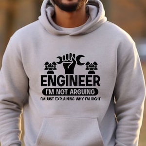 May include: Gray hooded sweatshirt with a black graphic print that reads "Engineer I'm not arguing I'm just explaining why I'm right". The graphic also includes a wrench and two stylized figures wearing hard hats.