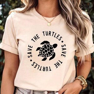 May include: A cream colored t-shirt with a black graphic of a sea turtle and the text "Save the Turtles. Save the Turtles."