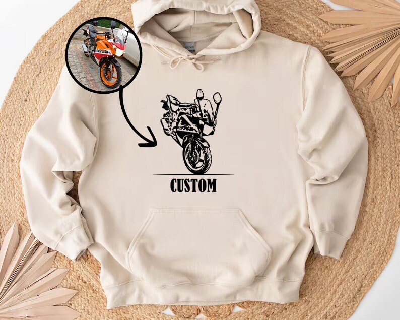 May include: A cream-colored hoodie with a black illustration of a motorcycle and the word "CUSTOM" printed on the front.