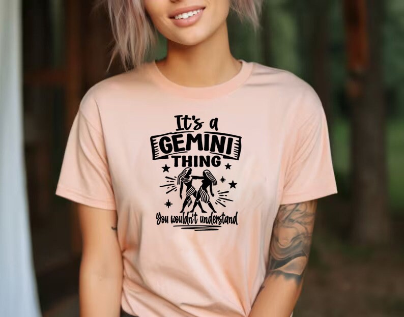 May include: A peach colored t-shirt with black text that reads 'It's a Gemini thing You wouldn't understand' with a black silhouette of two women holding hands.