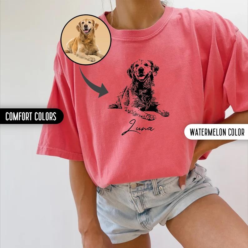 K&ouml;nnte beinhalten: Ein pinkfarbenes T-Shirt mit einer schwarzen Silhouette eines Hundes und dem Namen "Luna" darauf gedruckt. Das Shirt wird von einem Model getragen, das eine Jeans-Shorts tr&auml;gt.