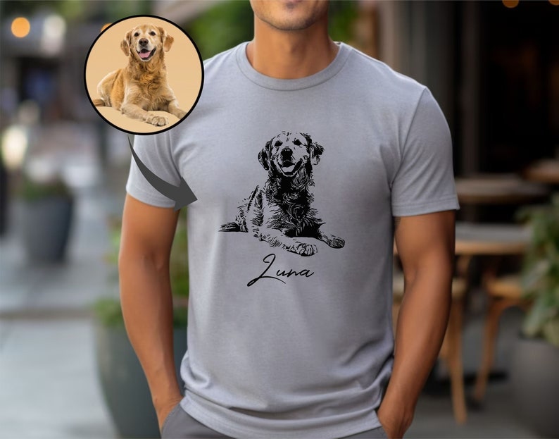 May include: A grey t-shirt featuring a black and white illustration of a dog lying down. The dog's name, "Luna", is written in cursive below the illustration.