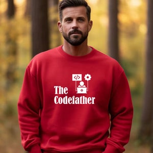 May include: Red sweatshirt with white text that reads "The Codefather" and a graphic of a person sitting at a computer with code and a gear.