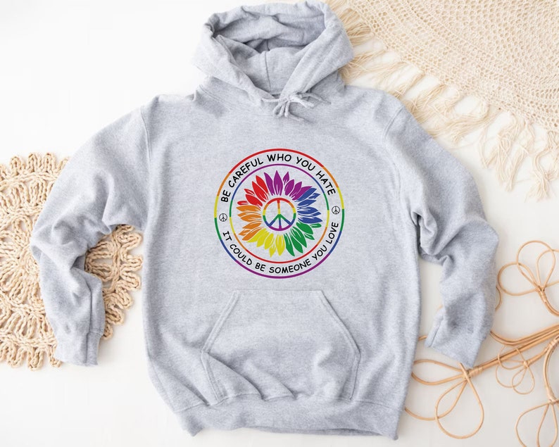 May include: A gray hooded sweatshirt with a rainbow peace sign and the text 'Be careful who you hate, it could be someone you love'.