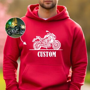 May include: Red hooded sweatshirt with a white outline of a motorcycle and the word "CUSTOM" printed on the front.