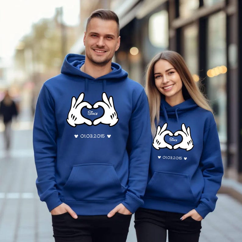 May include: Two matching blue hoodies with white Mickey Mouse-style hands forming a heart. The word "Since" is inside the heart, with the date "01.03.2015" below. The hoodies have a front pocket and a hood.