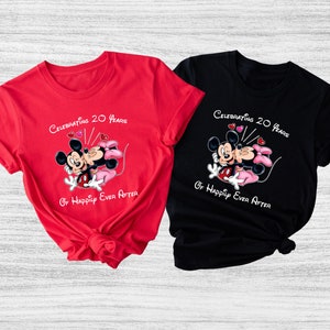May include: Two t-shirts, one red and one black, featuring a graphic of Mickey and Minnie Mouse kissing. The text on the shirts reads "Celebrating 20 Years Of Happily Ever After."