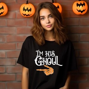 May include: Black t-shirt with the text "I'M HIS GHOUL" in white, and an orange skeleton hand pointing to the right. The shirt is a Halloween-themed design.