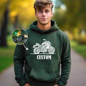 May include: A dark green hooded sweatshirt with a white outline of a motorcycle and the word "CUSTOM" printed on the front.