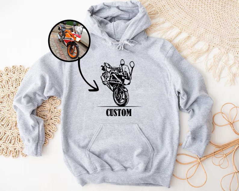 May include: Gray hooded sweatshirt with a black and white illustration of a motorcycle on the front. The text "CUSTOM" is printed below the motorcycle.