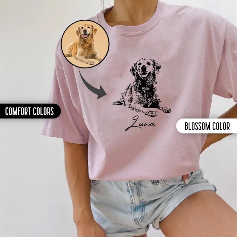 K&ouml;nnte beinhalten: Ein pinkfarbenes T-Shirt mit einer schwarz-wei&szlig;en Illustration eines Hundes. Der Hund liegt und der Text "Luna" steht darunter. Das Shirt wird von einem Model getragen, das eine Jeans-Shorts tr&auml;gt.