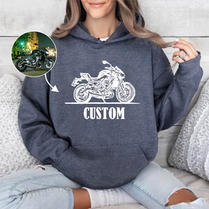 May include: A dark gray hoodie with a white outline of a motorcycle and the word "CUSTOM" printed on the front.