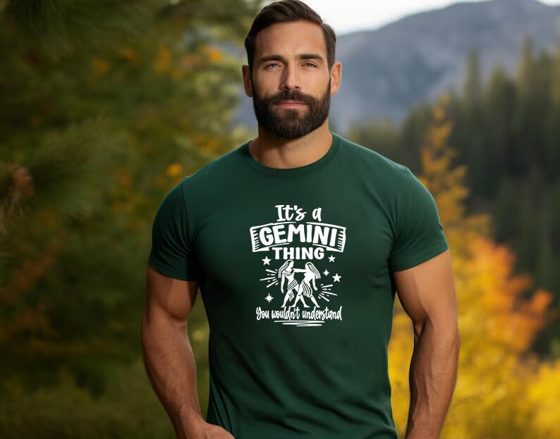 May include: A dark green t-shirt with the text "It's a GEMINI THING you wouldn't understand" in white. The graphic includes the Gemini zodiac symbol. The shirt is being worn by a person.