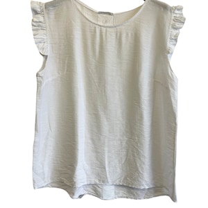 Puede incluir: Top blanco sin mangas con mangas con volantes y un escote redondo. La parte superior está hecha de una tela ligera y tiene un ajuste ligeramente holgado.