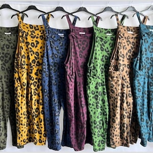 Könnte beinhalten: Eine Kollektion von Leopardenmuster-Overalls in verschiedenen Farben, darunter Orange, Olivgrün, Gelb, Marineblau, Lila, Grün, Beige, Türkis und Grau. Jeder Overall hängt an einem schwarzen Kleiderbügel vor einem weißen Hintergrund.