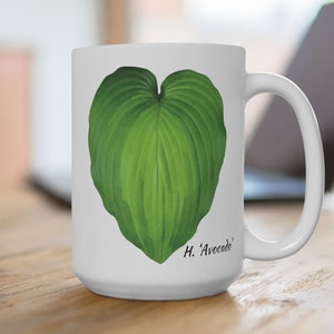 May include: White ceramic mug with a green heart-shaped leaf design and the text "H. 'Avocado'" printed on the bottom.
