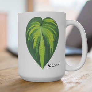 May include: White ceramic mug with a green and yellow hosta leaf printed on it. The leaf is shaped like a heart and the text "H. 'June'" is printed below it.