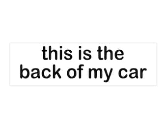 May include: A white rectangular sticker with the phrase "this is the back of my car" printed in black, bold, sans-serif font. The text is centered on the sticker.