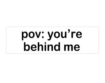 May include: A white rectangular sticker with the text "pov: you're behind me" in black, sans-serif font. The sticker is designed to be placed on a surface.