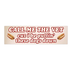 May include: A rectangular bumper sticker with the text "CALL ME THE VET cuz i be puttin' these dogs down" in red, stylized font. Two hot dogs are on either side of the text. The background is a light tan color.