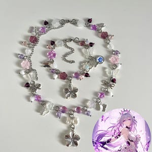 Puede incluir: Un conjunto de collar y pulsera con temática floral y de mariposas. La joyería presenta cadenas plateadas, cuentas transparentes, rosas y moradas, y colgantes de flores plateadas. En la imagen hay un gráfico redondo de una mujer con cabello morado.