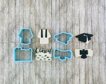 May include: A set of eight blue plastic cookie cutters in various graduation-themed shapes, including a cap, diploma, gown, and the words "Class of".