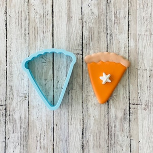 May include: A blue plastic pie cutter and a decorated orange pie cookie with a white star on top.