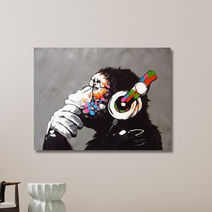 May include: A black and white painting of a monkey wearing headphones with colorful accents. The monkey is thinking and has a thoughtful expression on its face.
