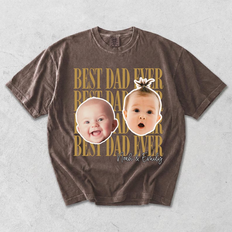 Może przedstawiać: Brązowa koszulka z napisem "BEST DAD EVER" w kolorze złotym. Koszulka przedstawia dwie twarze dziecka oraz imiona "Noah & Emily" w ozdobnej czcionce. Koszulka ma wygląd vintage.