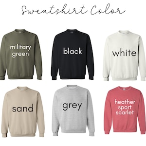 K&ouml;nnte beinhalten: Eine Auswahl an Sweatshirts mit Rundhalsausschnitt in verschiedenen Farben, darunter Milit&auml;rgr&uuml;n, Schwarz, Wei&szlig;, Sand, Grau und Heather Sport Scarlet. Jedes Sweatshirt hat den Farbnamen in Wei&szlig; aufgedruckt. Der Text "Sweatshirt Color" steht oben.