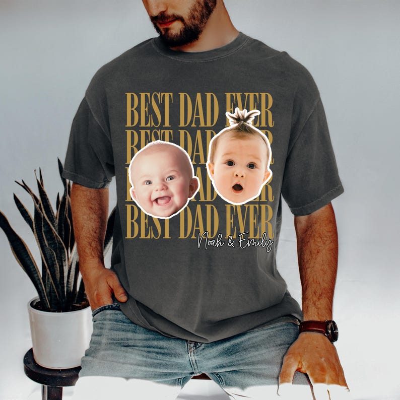 Może przedstawiać: Ciemnoszara koszulka z napisem "BEST DAD EVER" w złotym kolorze. Na koszulce znajdują się dwa zdjęcia dzieci oraz imiona "Noah & Emily". Wygodna, codzienna koszulka.