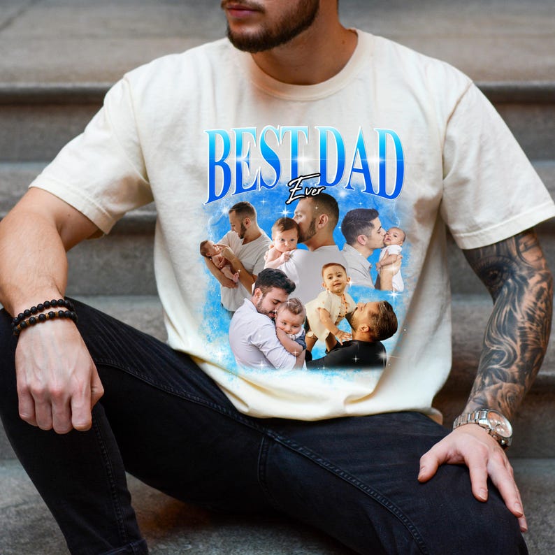 May include: Cream-colored t-shirt with the text "BEST DAD Ever" in blue, featuring a collage of images of a father with his baby. The shirt is a casual wear item.