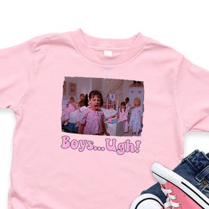 May include: Pink toddler t-shirt with a movie still graphic and the text "Boys... Ugh!". The shirt is paired with blue denim jeans and pink canvas sneakers.