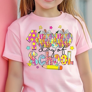 May include: A pink t-shirt with a colorful graphic design that says "100 days of school" with two pumpkins and a pencil.