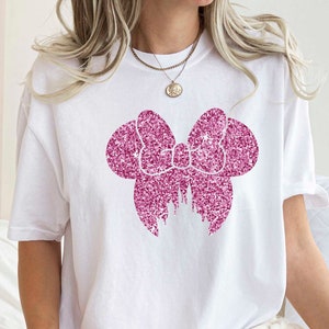 May include: White t-shirt with a pink glitter bow and castle design.