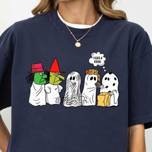 May include: A navy blue t-shirt with a graphic of the Peanuts characters dressed as ghosts and a witch. The text "I GOT A ROCK" is in a thought bubble above the characters.