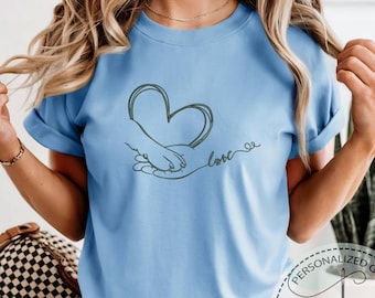 Camiseta con corazón bordado y diseño de pata, colores cómodos, mano y pata humanas, arte de amor con una mano agarrando una pata, diseño minimalista, regalo para ella