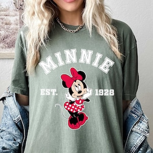 May include: A green t-shirt with a white graphic of Minnie Mouse and the text "MINNIE EST. 1928".