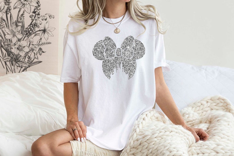 May include: A white t-shirt with a black glitter bow design.