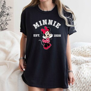 May include: Black t-shirt with a white graphic of Minnie Mouse and the text "Minnie Est. 1928".