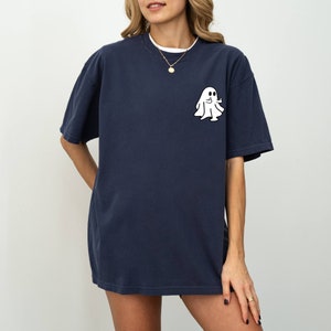 May include: A navy blue oversized t-shirt with a white ghost graphic giving a thumbs up. The ghost is wearing a sheet and has two eyes.