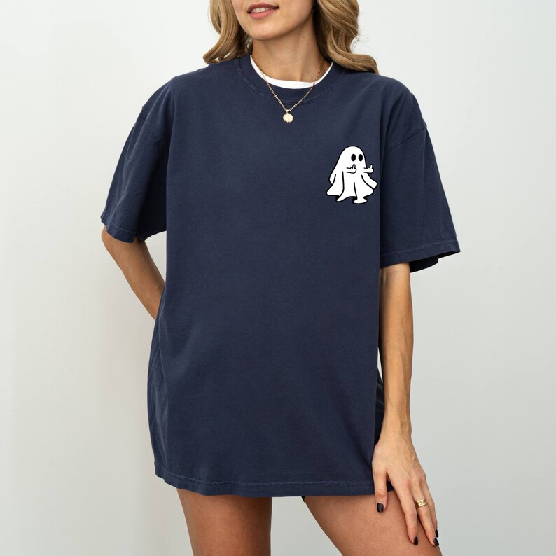 May include: A navy blue oversized t-shirt with a white ghost graphic giving a thumbs up. The ghost is wearing a sheet and has two eyes.