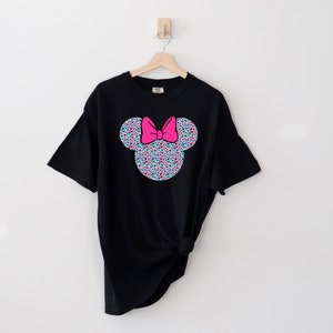 以下が含まれることがあります： カラフルなミニーマウスの頭のグラフィックがプリントされた黒いTシャツ。グラフィックは小さなカラフルなドットで構成されており、ピンクのリボンが付いています。