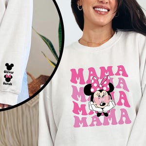 Puede incluir: Sudadera blanca con un gr&aacute;fico rosa y blanco de Minnie Mouse con el texto "MAMA" repetido en un patr&oacute;n degradado.