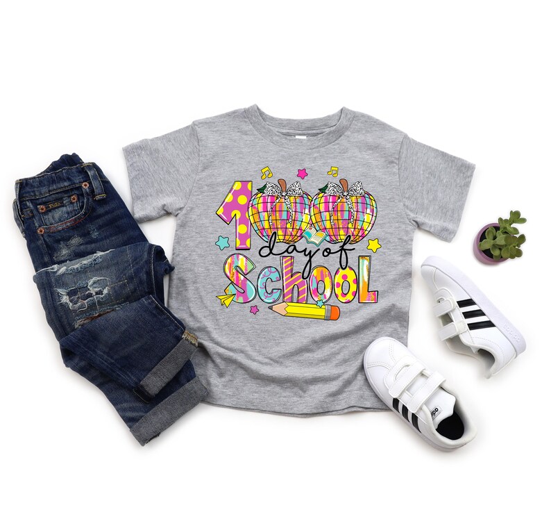 May include: A gray t-shirt with a colorful graphic that says "100 day of school" with two pumpkins and a pencil.