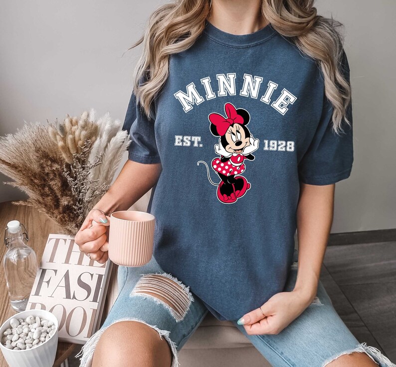May include: A navy blue t-shirt with a white graphic of Minnie Mouse and the text "Minnie Est. 1928".