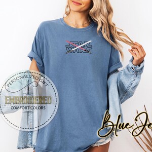 May include: A blue t-shirt featuring the text "STAR WARS" and a graphic of two crossed lightsabers.