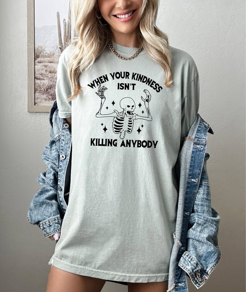 May include: A light green t-shirt with a black skeleton graphic and the text "When your kindness isn't killing anybody".