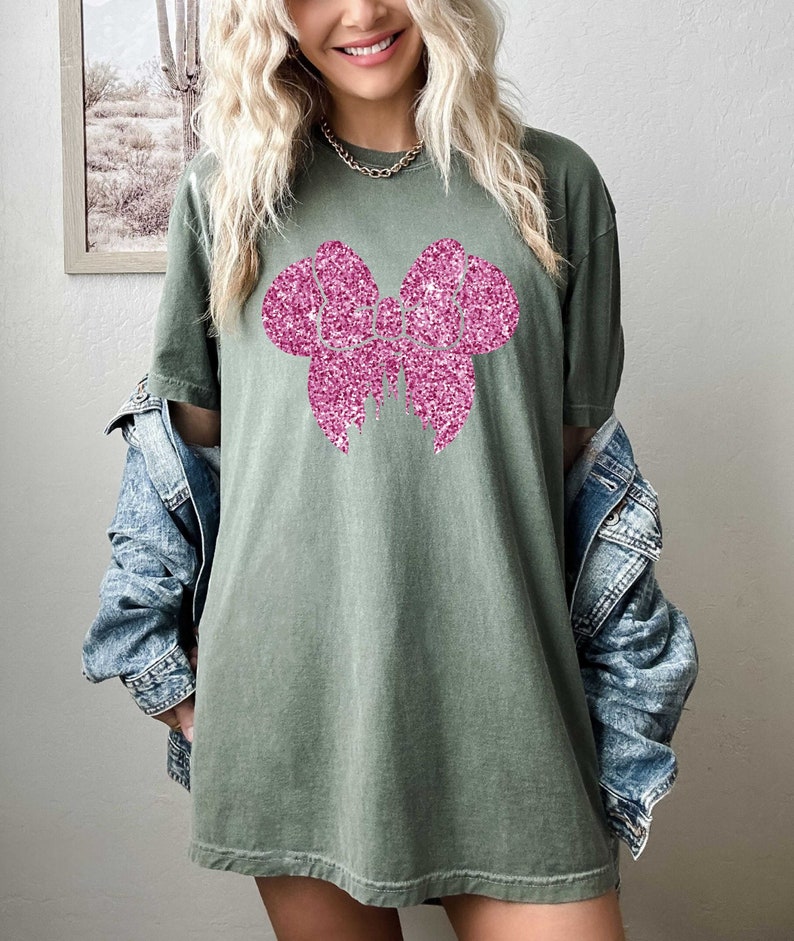 May include: A green oversized t-shirt with a pink glitter bow design.