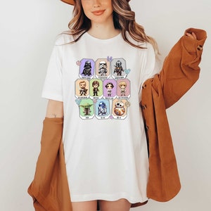 May include: White t-shirt with a colorful graphic of Star Wars characters. The characters are in a grid pattern and include Darth Vader, Stormtrooper, Yoda, R2-D2, and others.